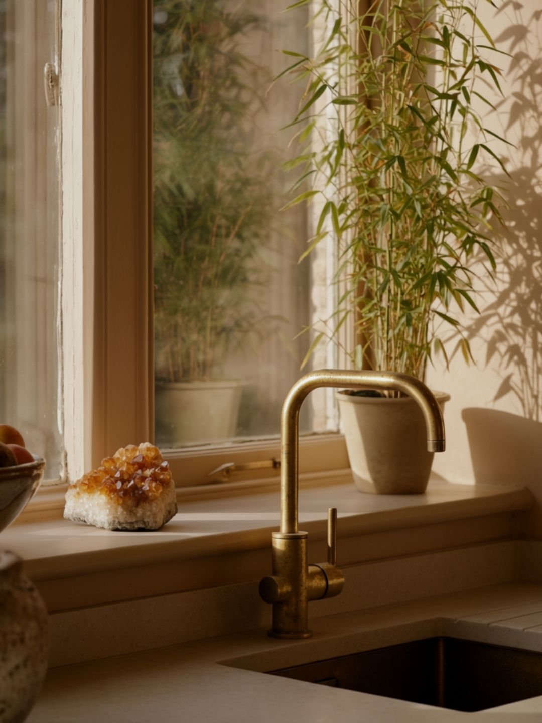 Kitchen sink with gold faucet and plants in the background citrine crystal resting on the windowsill