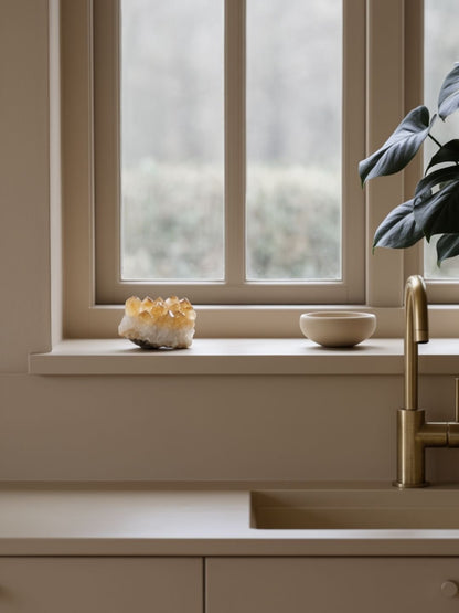 Window sill with decorative items and a crystal and a plant in a kitchen setting