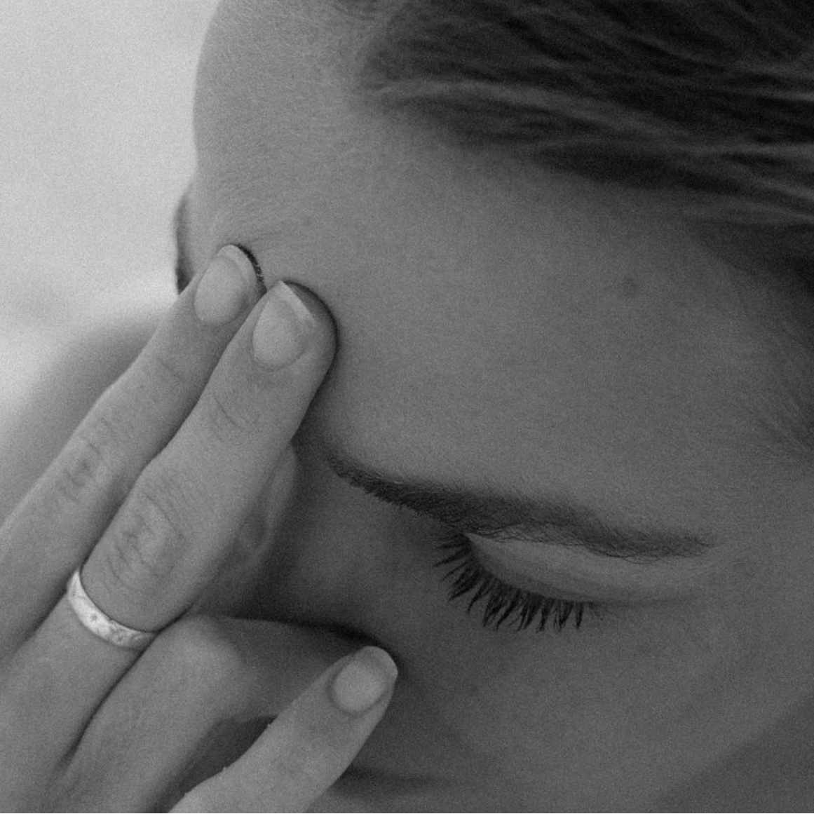 Black and white close-up of a person with a finger on their face