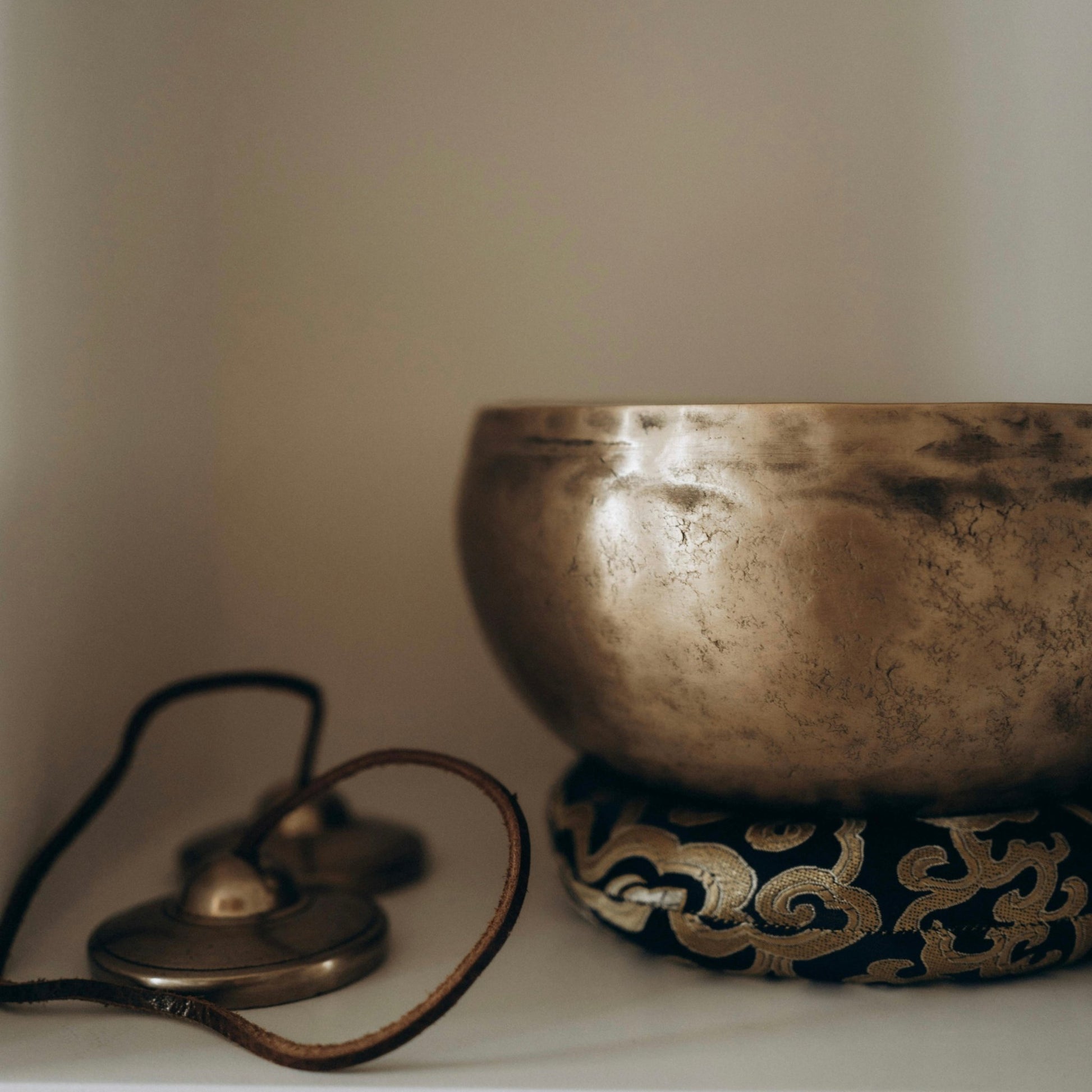 meditation singing bowl resting on felt ring with symbols next to it