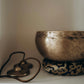 meditation singing bowl resting on felt ring with symbols next to it