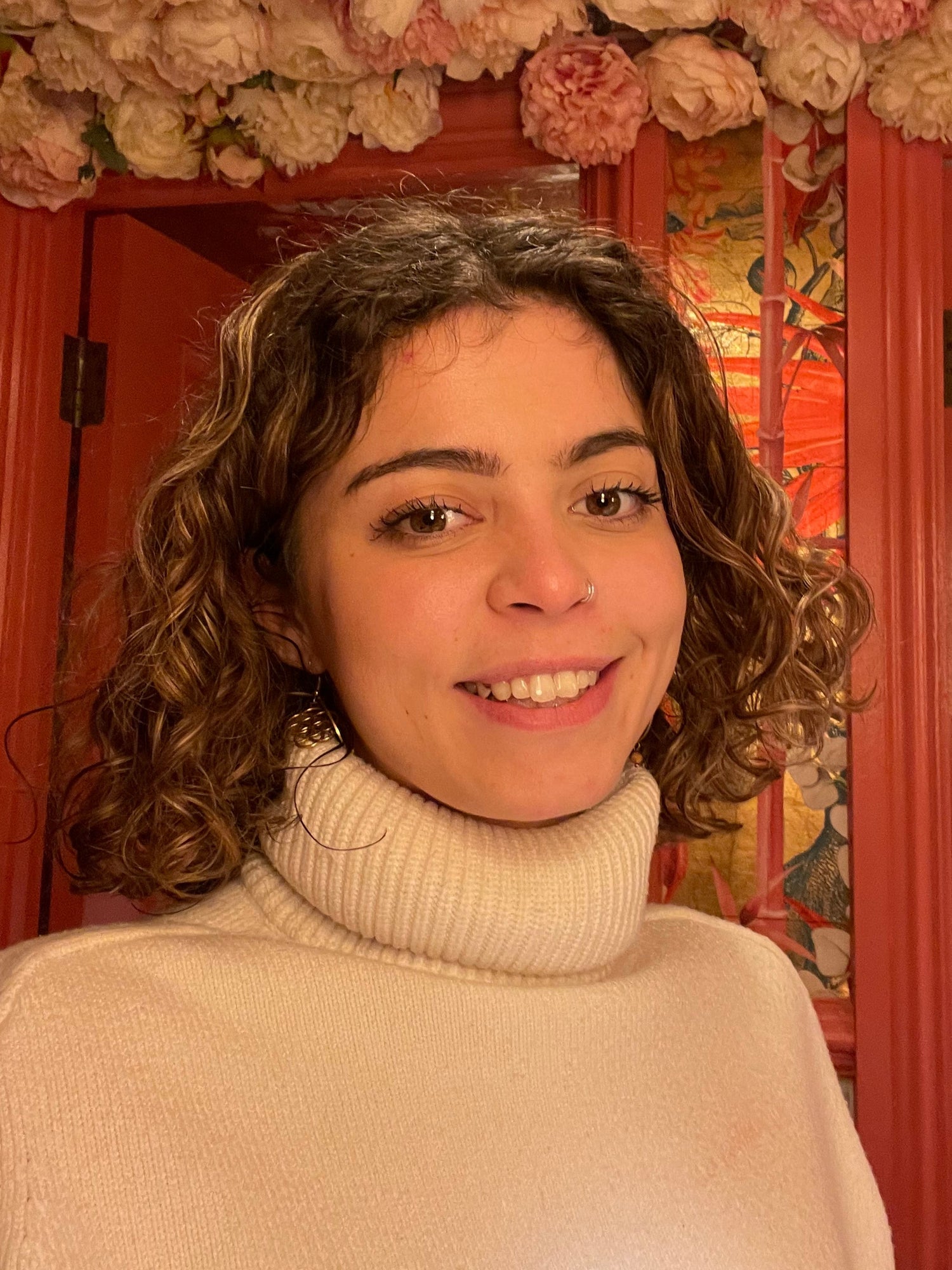 Woman smiling in front of a decorative wall with flowers and door