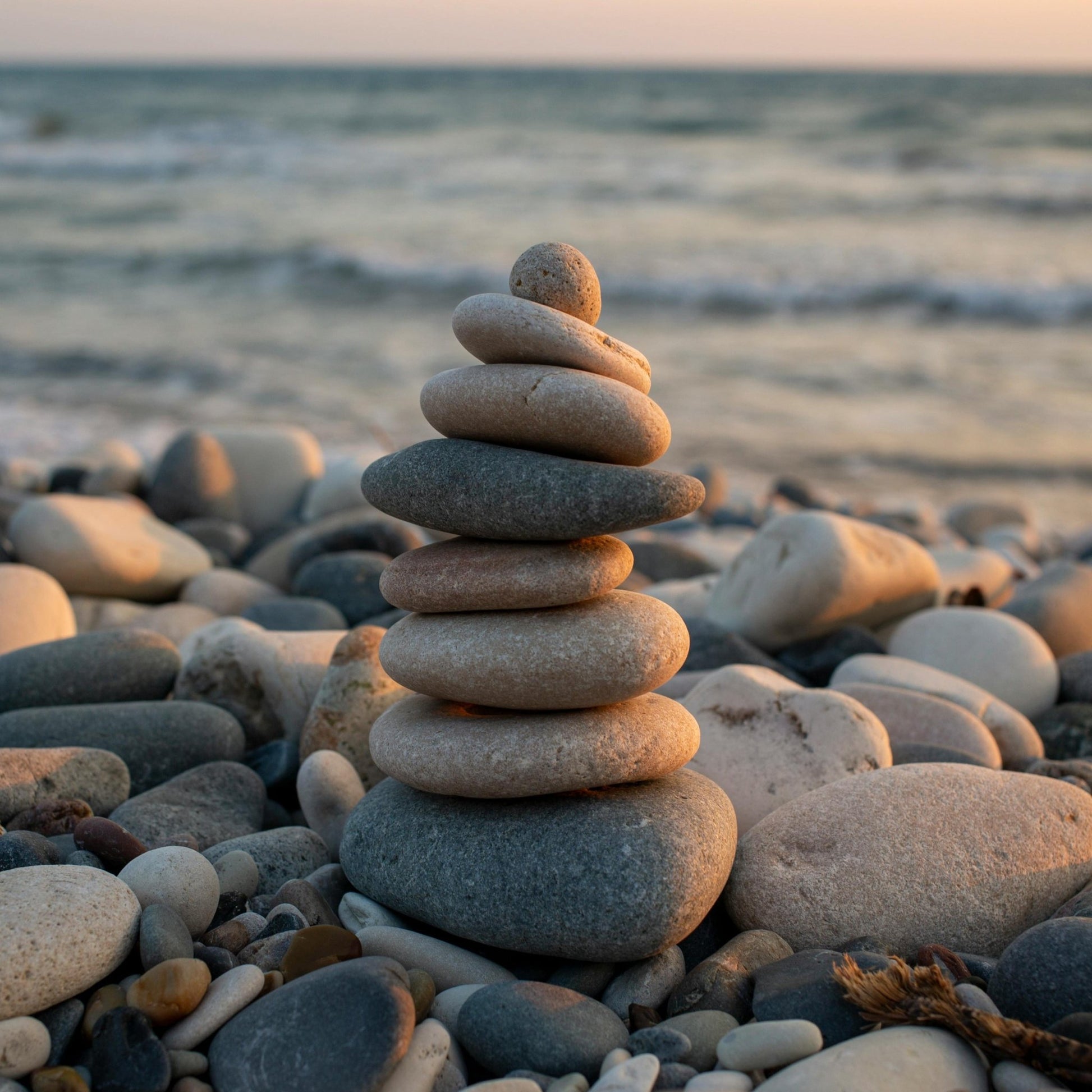 A stack of pebbles balanced on top of each other on a rocky beach with the ocean in the background.