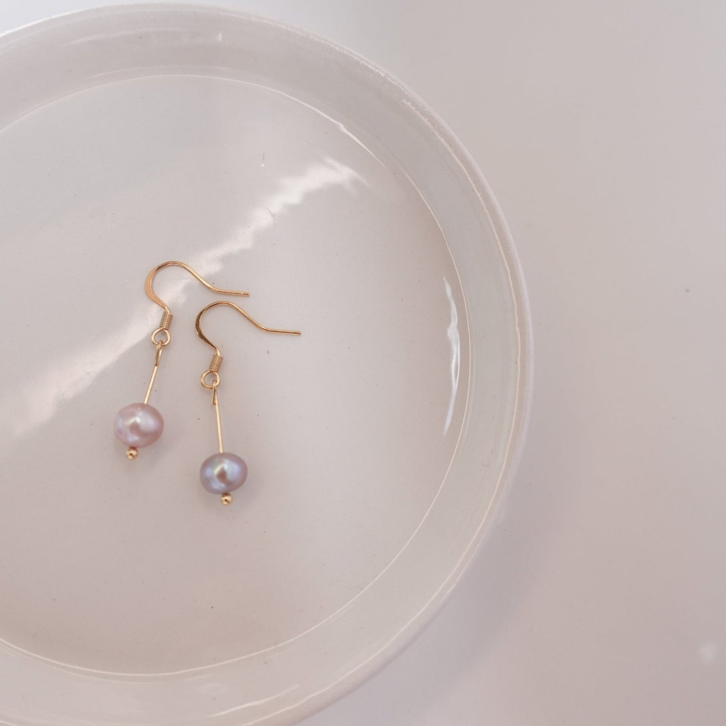 pink pearls with gold plated 18c dangle hardware laying on a ceramic plate 